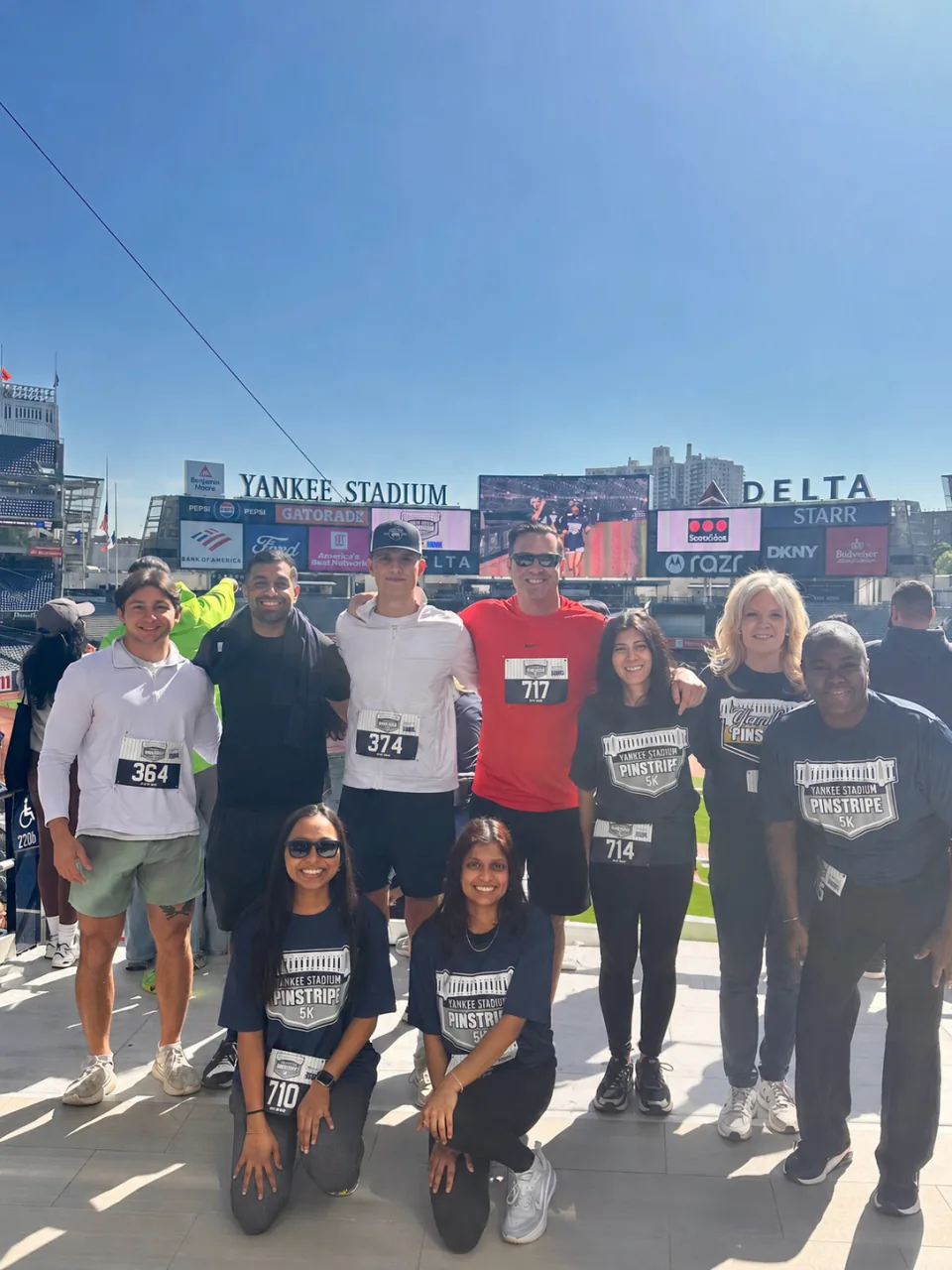 Action team members together at the Pinstripe 5K at Yankee Stadium, wearing race bibs