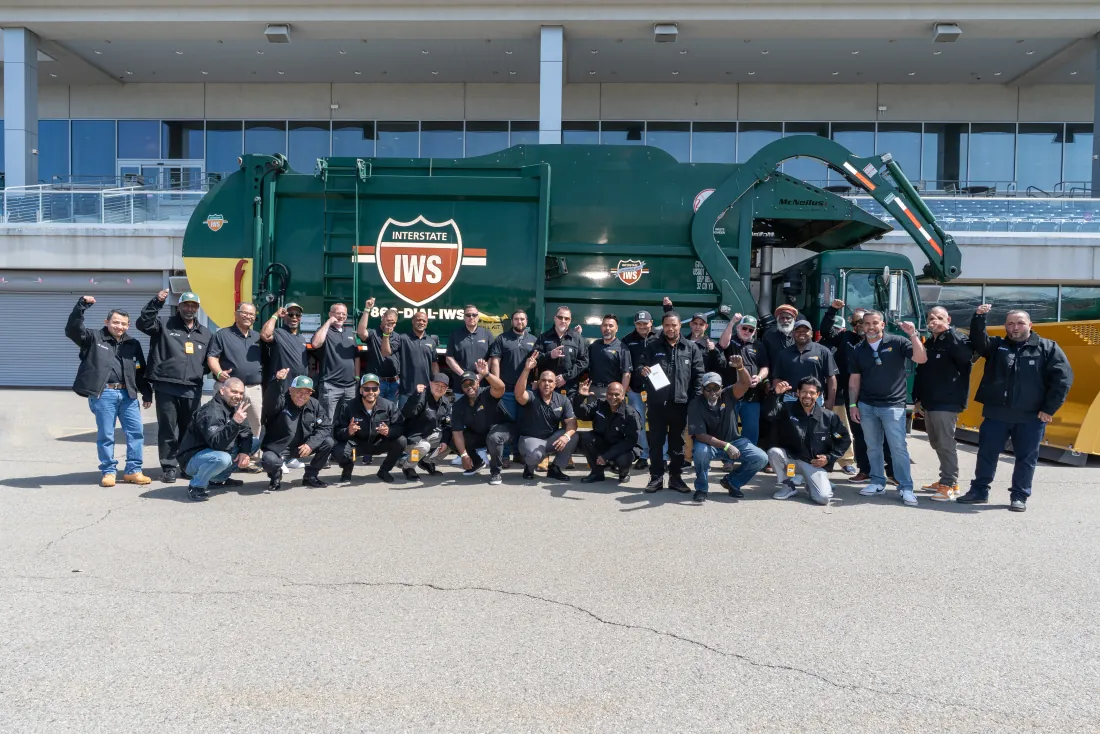 A large group of employees posing together in front of a collection truck